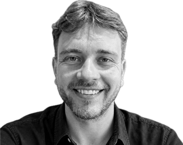 Portrait of Andrius Kleinas, smiling, in a dark shirt